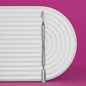 A stainless steel manicure pusher with a rounded wide pusher and cleaner, displayed on a white ribbed surface with a pink background.