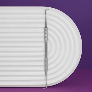 A double-ended pedicure curette with a white handle, placed on a white surface with a purple background.