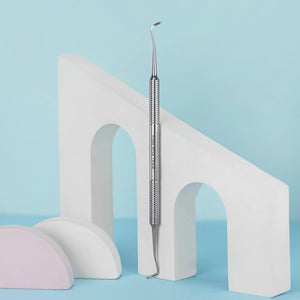 A double-ended curette pedicure tool with a corrugated handle, displayed against a light blue background with a white decorative arch and a pink sponge.