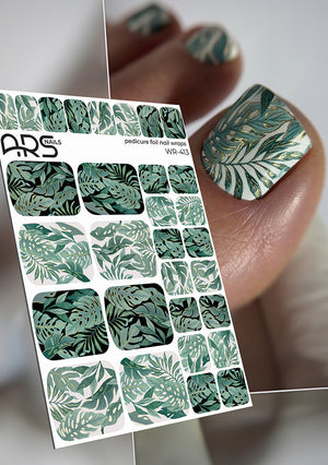 Nail art foil sheet with green leaf pattern held by a hand with matching nails.