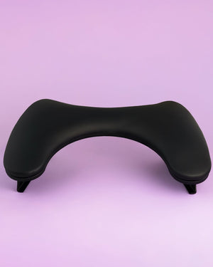 Black ergonomic wrist rest on a light purple background. Armrest in black