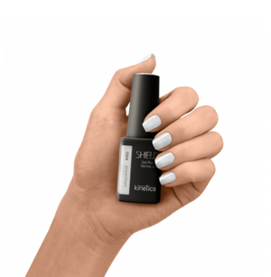 A bottle of SHIELD Gel Polish in a silver pearl effect color, with a label that reads 'KINETICS #002 Bridal dress'. The bottle has a matte black finish and a hand-painted cap.