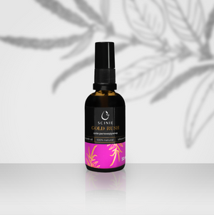 A black bottle with a pump dispenser labeled 'Scinie GOLD RUSH' containing regenerating skin oil, placed on a white surface with a shadow of a plant leaf overhead.