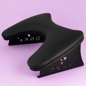 Black ergonomic wrist rest on a light purple background. Armrest in black