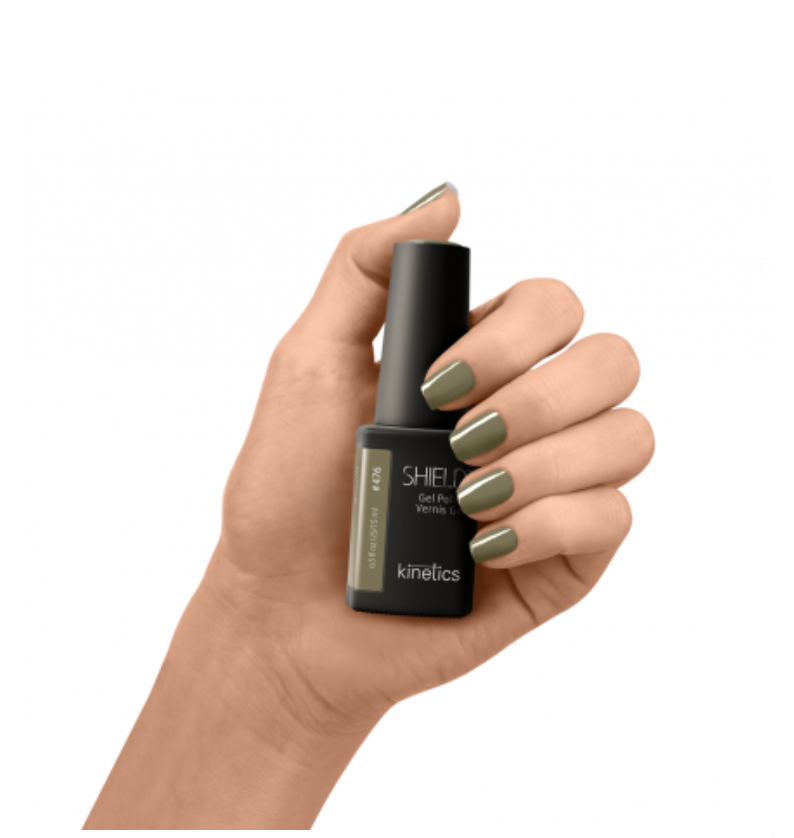 Hand holding a bottle of nail polish with matching green nails on a white background
