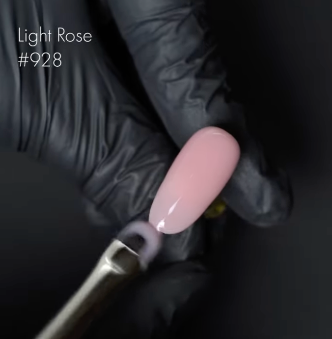 Nail polish brush with light pink nail tip and black glove on dark background