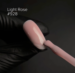 Light rose nail polish being applied with a brush on a dark background