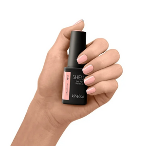 Hand holding a nail polish bottle labeled 'SHIELD' by 'kinetics' on a white background