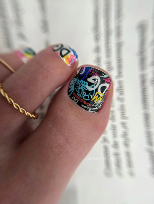 Nail with colorful design held by a hand against a blurred background