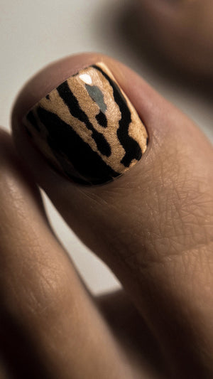 Nail with black and gold zebra pattern on a neutral background