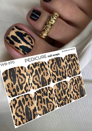 Leopard print nail wraps with a hand model wearing a gold ring and black and gold nail design.
