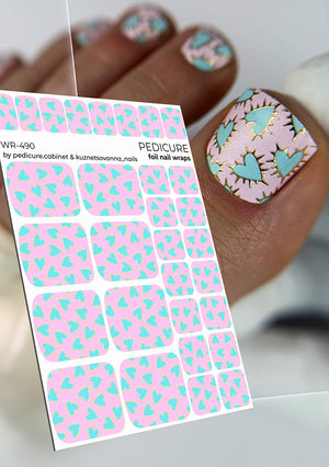 Sheet of pink and blue heart-patterned pedicure nail wraps with a hand displaying similar nail art