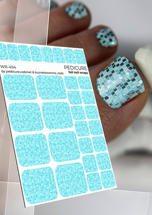 Sheet of blue pedicure nail foil wraps with a hand displaying applied foil on nails.