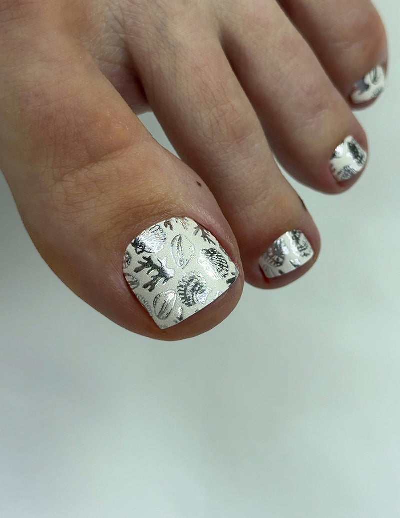 Close-up of toes with silver nail polish on a white background