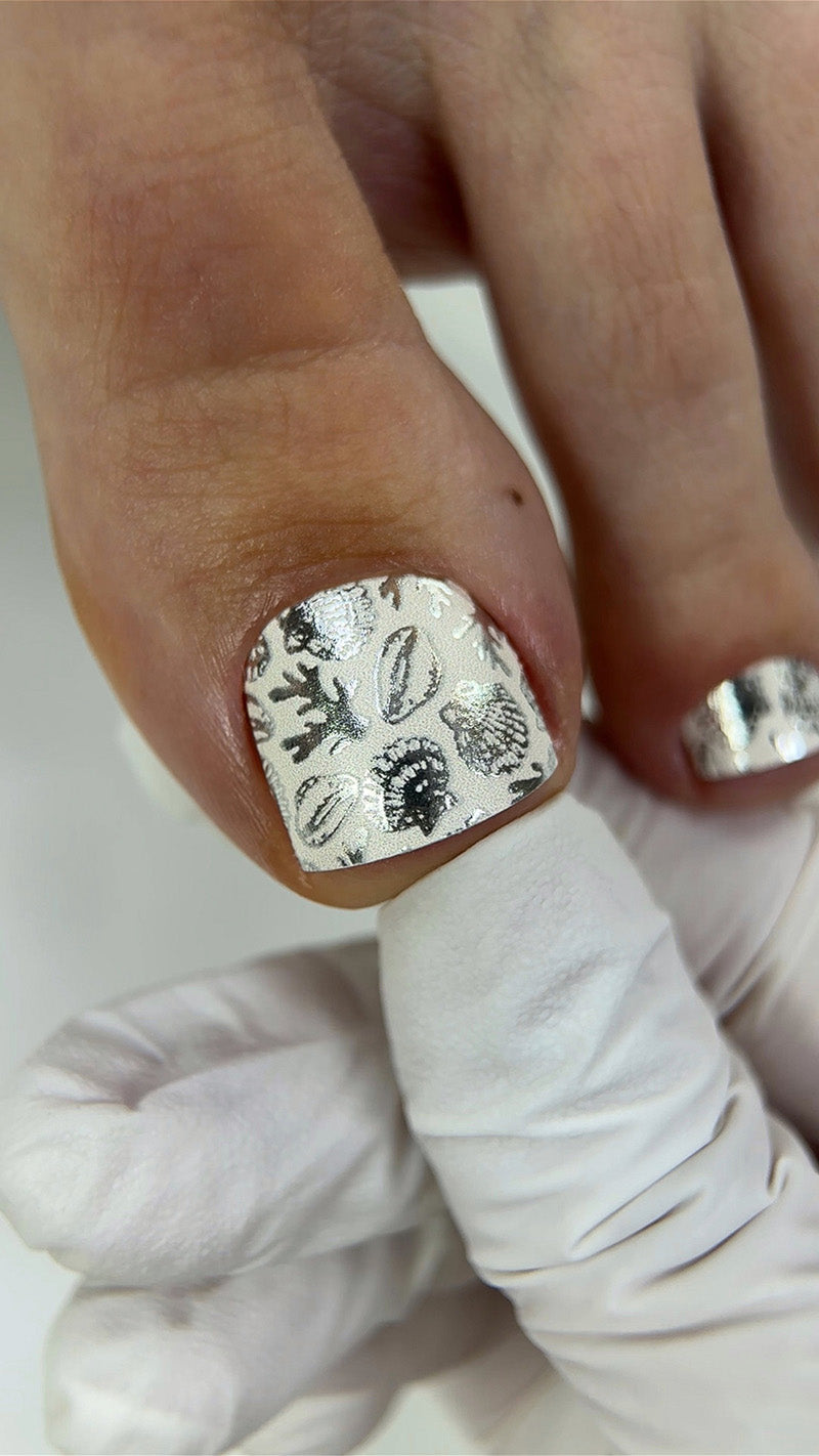 Close-up of a hand with a silver nail design on a white background
