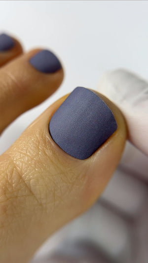 Close-up of a hand with dark blue nail polish on a blurred background