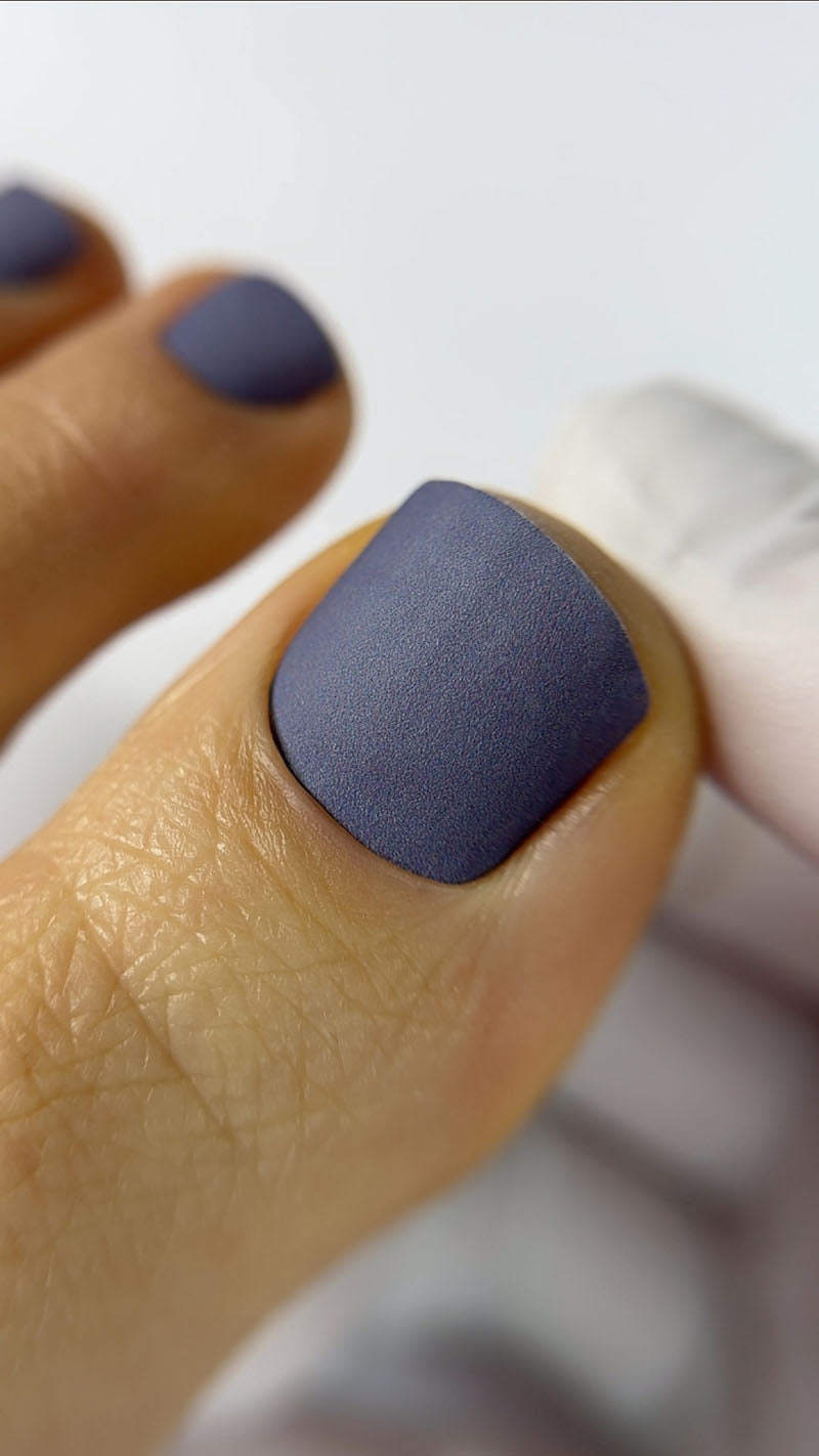 Close-up of a hand with dark blue nail polish on a blurred background