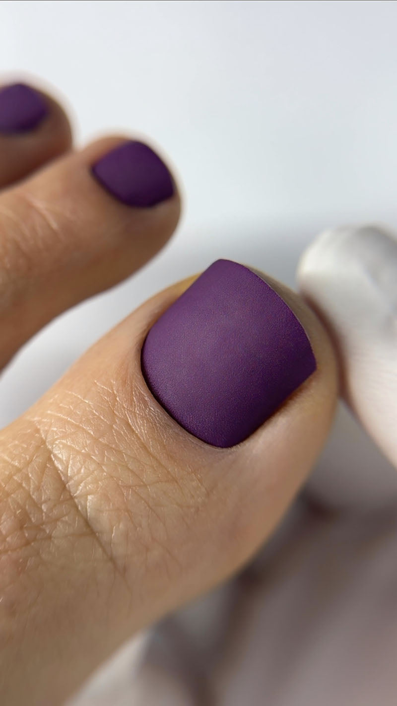 Close-up of a hand with purple nail polish on a white background