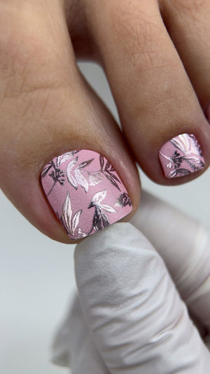 Nail art with pink floral design on a neutral background