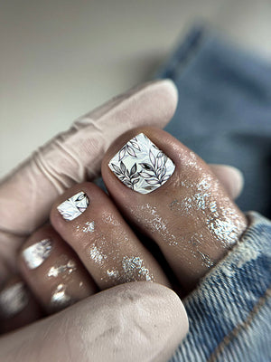 Close-up of a hand with silver nail art and a silver ring.