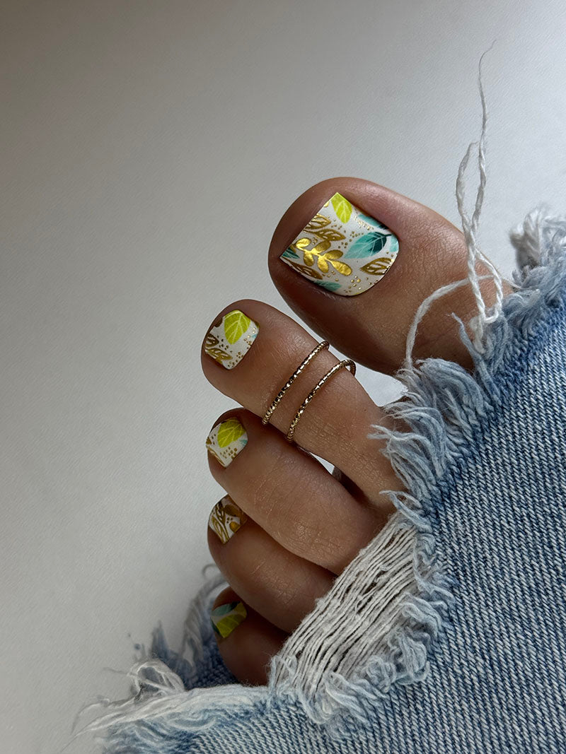 Close-up of a foot with floral nail design and denim fabric