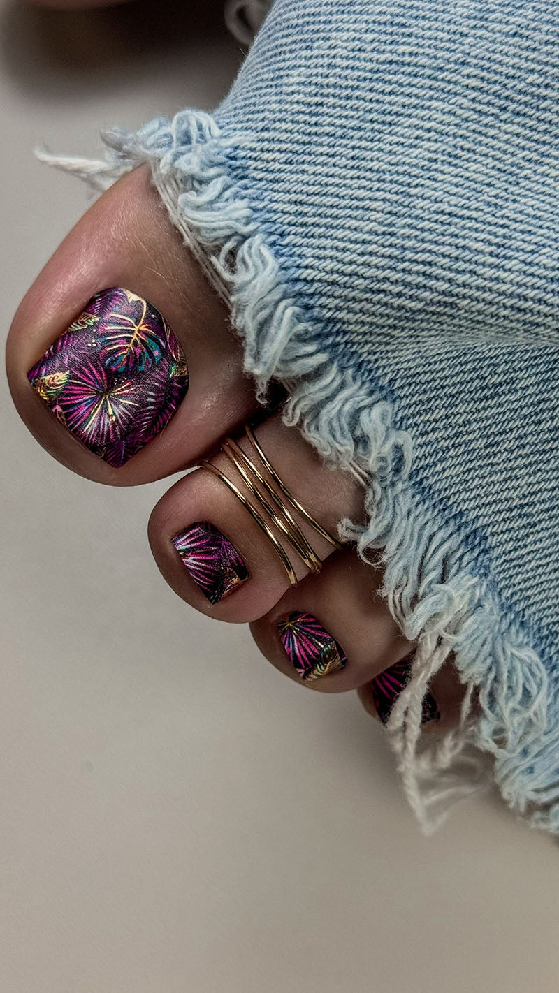 Close-up of a hand with colorful nail design wearing denim jeans.