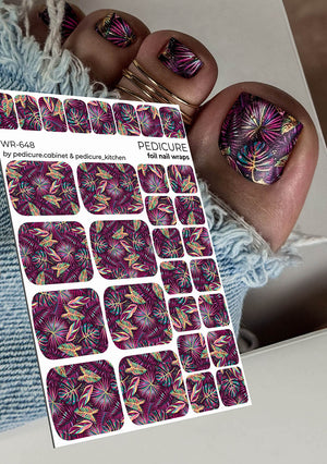 Foil pedicure nail wraps with purple and gold floral design held by a hand