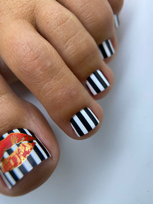 Close-up of toes with black and white striped nail design on a white background