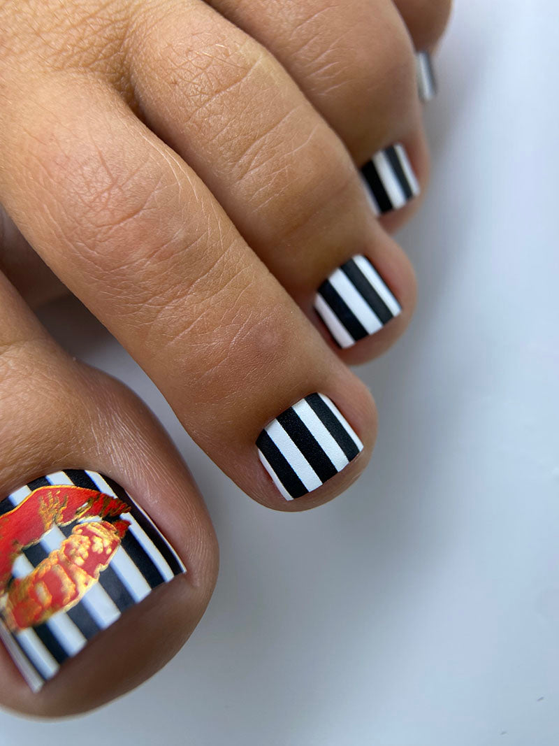 Close-up of toes with black and white striped nail design on a white background