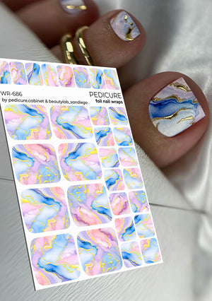 Nail foil pedicure wrap sheet with colorful marble design next to a hand with painted nails.