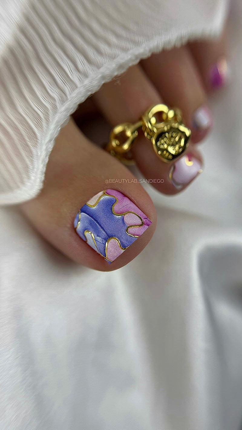 Close-up of a hand with colorful nail art wearing a gold lock-shaped ring on a white background.