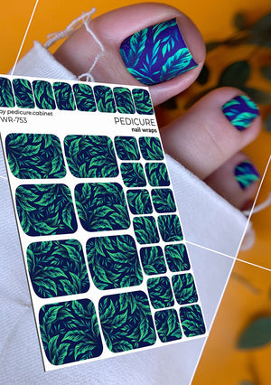 Nail wrap sheet with green leaf pattern and applied nail design on a blurred background