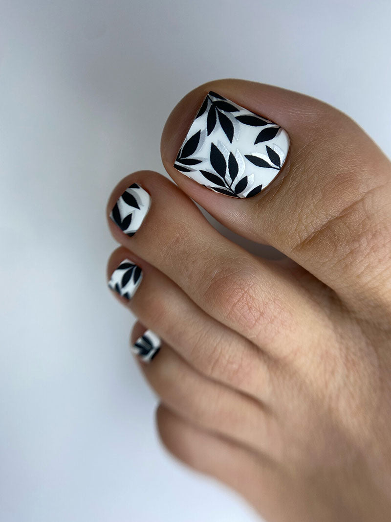 Toe nail with black and white pattern on a neutral background
