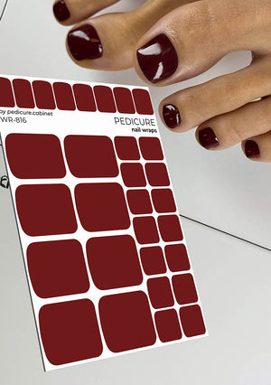 Sheet of red nail wraps with a hand holding them, on a light background