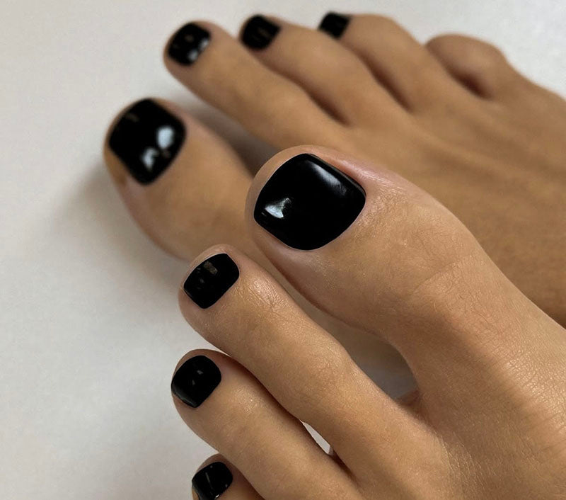 Close-up of toes with black nail polish on a light background
