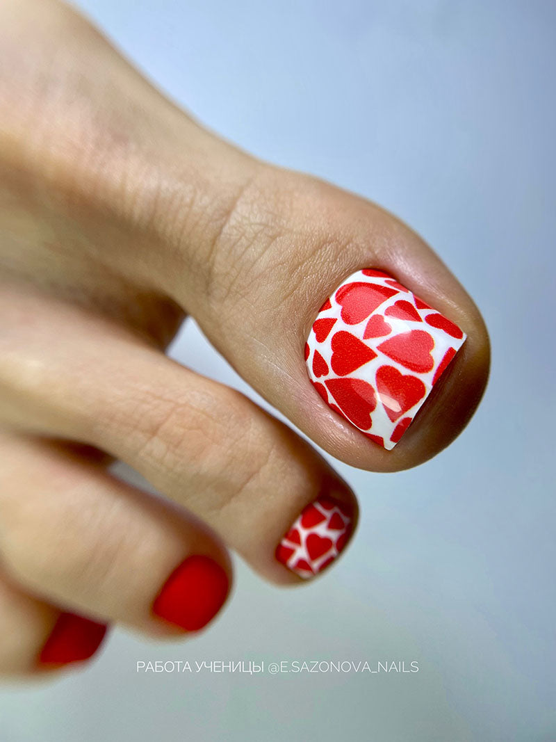 Nail art with red heart patterns on a light background