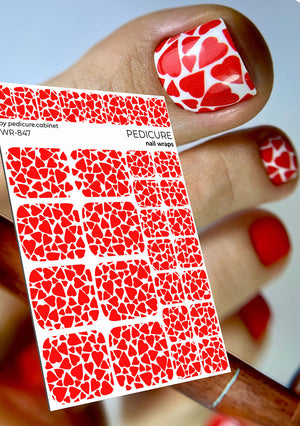 Red heart patterned nail wraps with a hand displaying red nail polish.