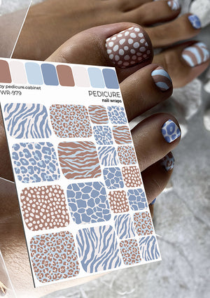 Nail wrap with various patterns held by a hand with painted nails.