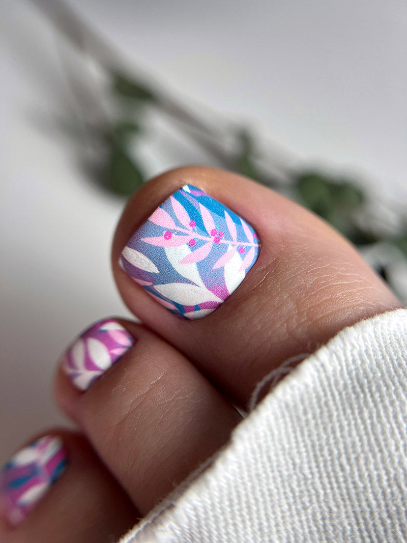 Close-up of a hand with colorful nail art against a blurred background