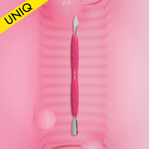 A manicure pusher with a silicone handle in pink color, with a metal working part, placed on a pink background with a water droplet and a bubble nearby.