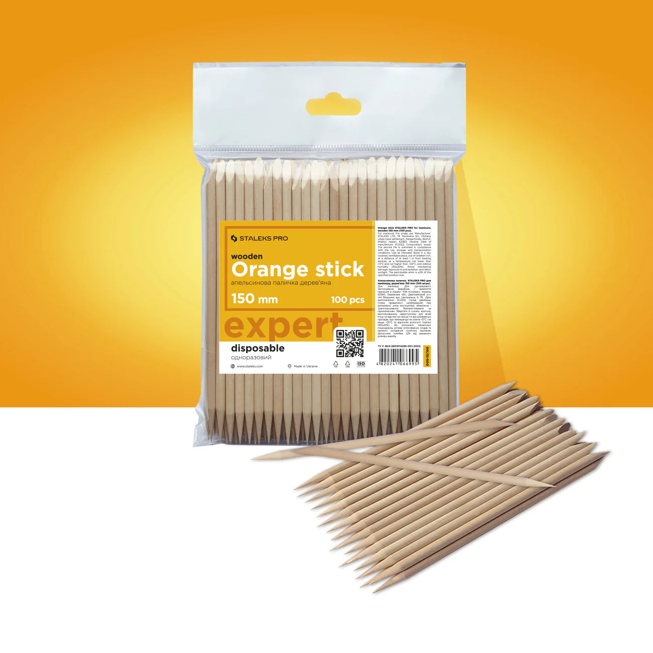 A pack of orange stick manicure tools made from natural wood, displayed against an orange background.
