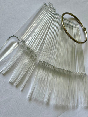 A set of transparent stiletto nail art tips displayed on a ring.
