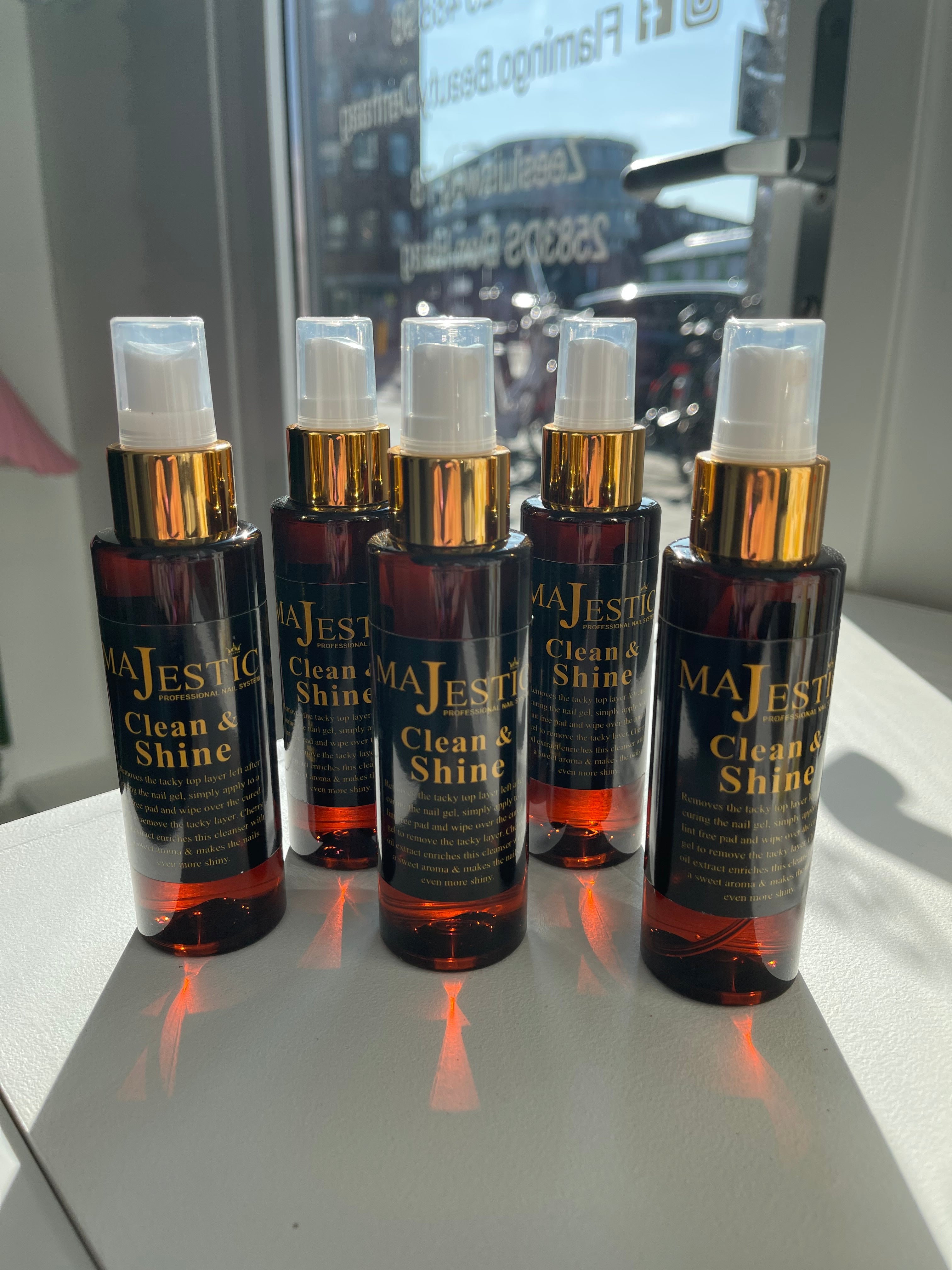 Multiple bottles of MaJestic Clean&Shine nail product displayed, with clear pink liquid and spray tops.