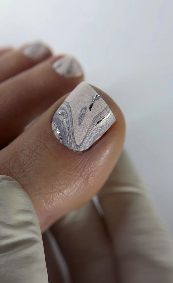 Nail with marble design held by a hand against a neutral background