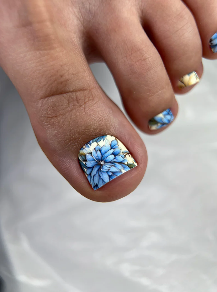 Close-up of a hand with floral nail art on a white background