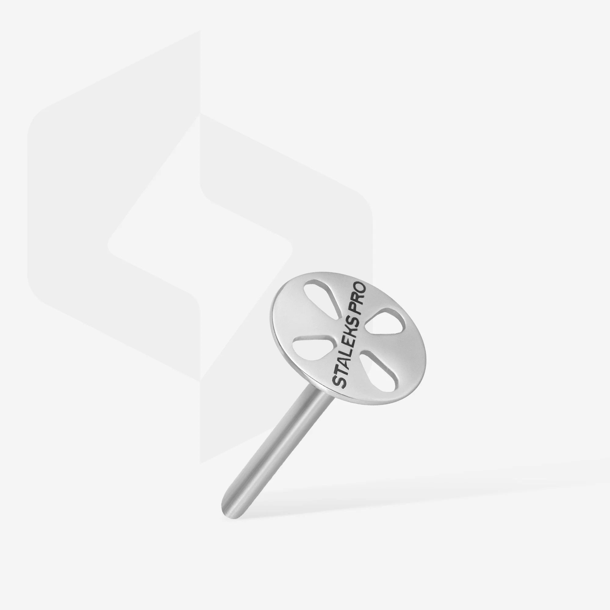 A metal pedicure disc with the brand name STALEKS PRO on it, displayed on a purple stand against a purple background.