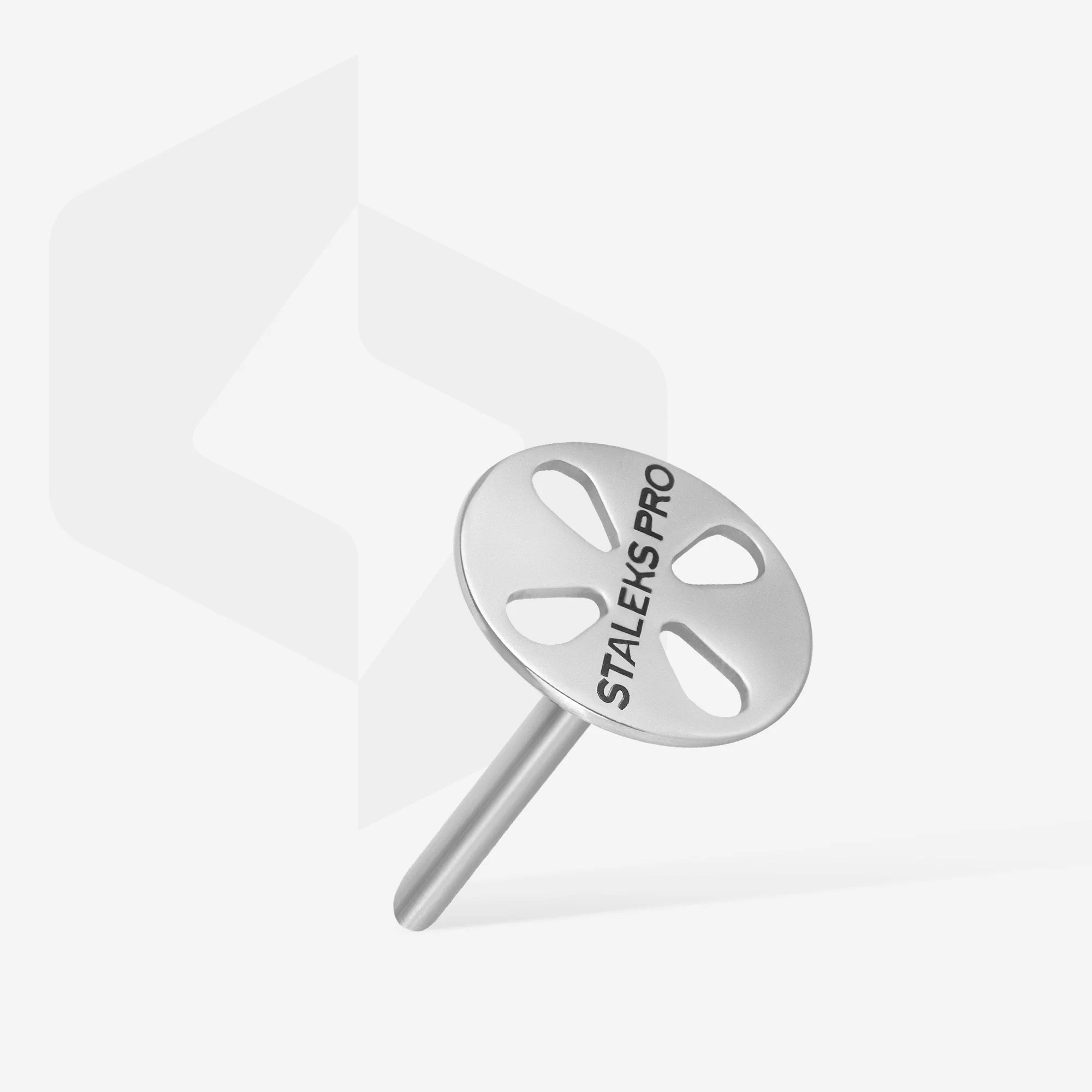 A metal pedicure disc with the brand name STALEKS PRO on it, displayed on a purple stand against a purple background.