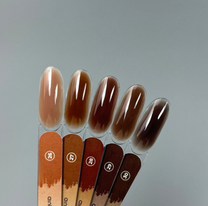 Set of brown nail polish swatches on a clear stand against a gray background