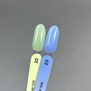 Two artificial nail tips swatched with polish colors 22 and 23 on a gradient gray background. Color 22 is a pale mint green, and color 23 is a soft sky blue.