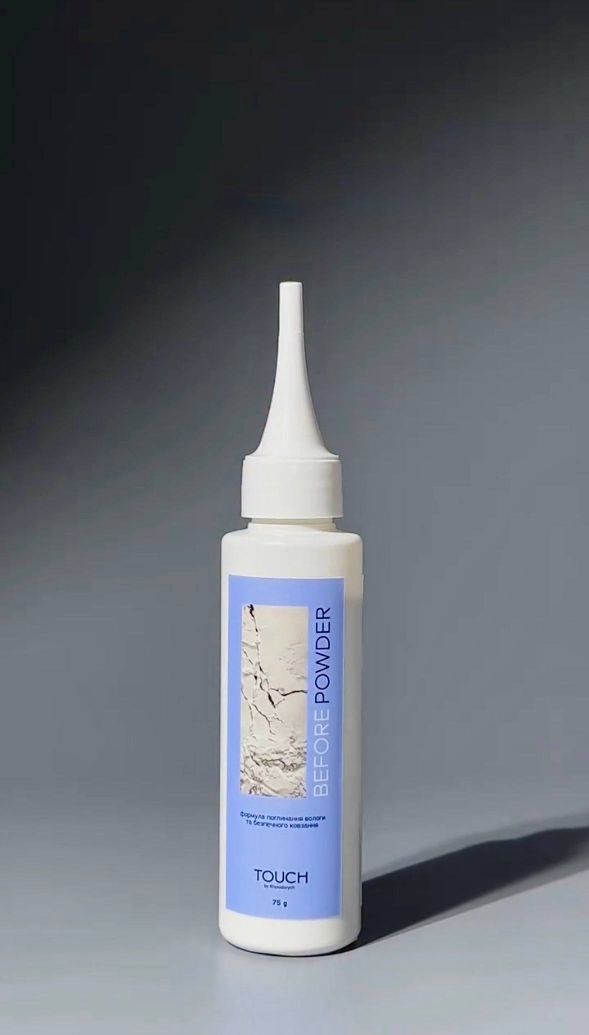 A white squeeze bottle of TOUCH Before Powder makeup with a light blue label, set against a dark gray gradient background.